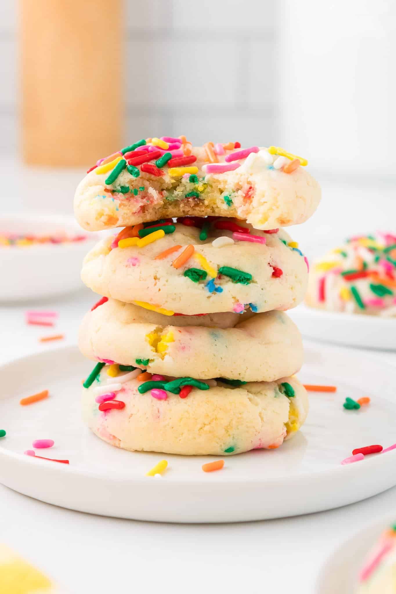 Funfetti cake mix cookies in a stack on a plate with a bite taken out