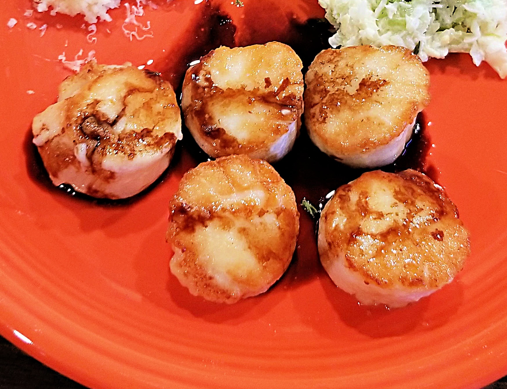 pan fried scallops with balsamic reduction on orange plate
